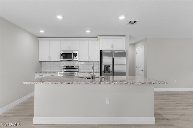 365 Woodburn Dr, Lehigh Acres, FL 33972 - kitchen with stainless steel appliances, a sink, a kitchen island with sink, baseboards, and white cabinetry