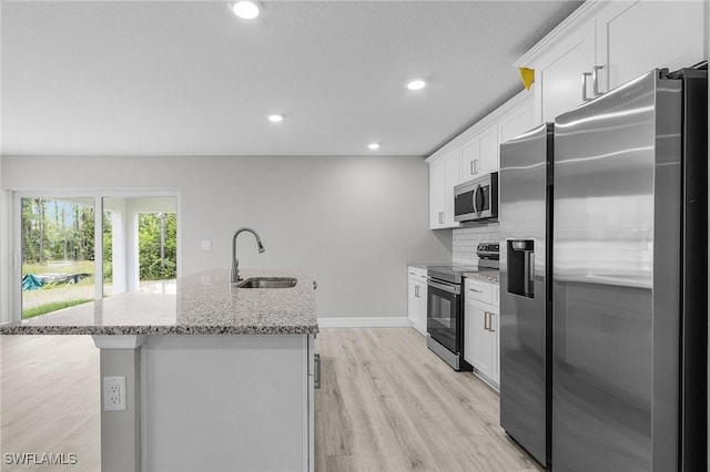365 Woodburn Dr, Lehigh Acres, FL 33972 - kitchen featuring stainless steel appliances, a sink, an island with sink, light wood-type flooring, and decorative backsplash