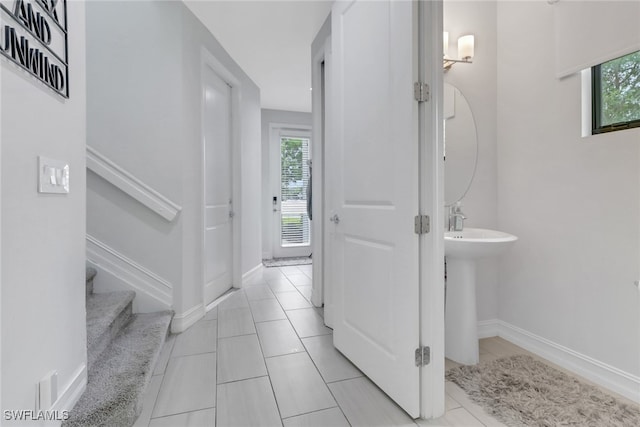 7501 Carnegie Way, Naples, FL 34119 - corridor featuring stairway, light tile patterned floors, baseboards, and a sink