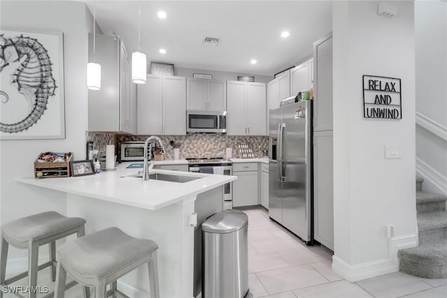 7501 Carnegie Way, Naples, FL 34119 - kitchen featuring stainless steel appliances, a peninsula, a sink, decorative backsplash, and a kitchen breakfast bar