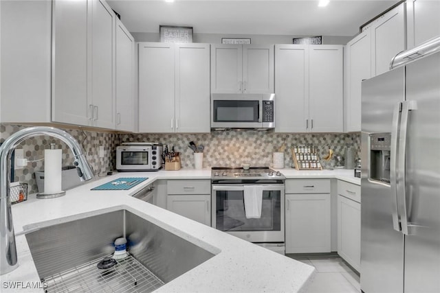7501 Carnegie Way, Naples, FL 34119 - kitchen featuring appliances with stainless steel finishes, a sink, backsplash, and light stone counters