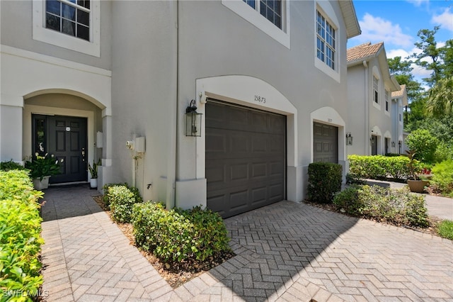 15873 Marcello Cir Unit 76, Naples, FL 34110 - view of exterior entry featuring stucco siding, a garage, a tile roof, and decorative driveway