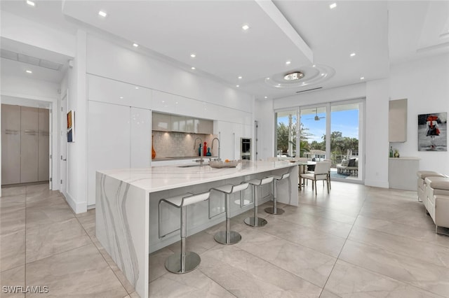 432 Bayside Ave, Naples, FL 34108 - kitchen with modern cabinets, white cabinets, a kitchen breakfast bar, backsplash, and recessed lighting