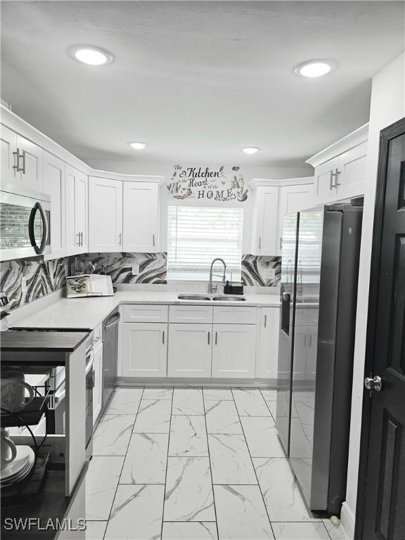 303 E 7th St, Lehigh Acres, FL 33972 - kitchen featuring appliances with stainless steel finishes, a sink, light marble finish floors, white cabinetry, and recessed lighting
