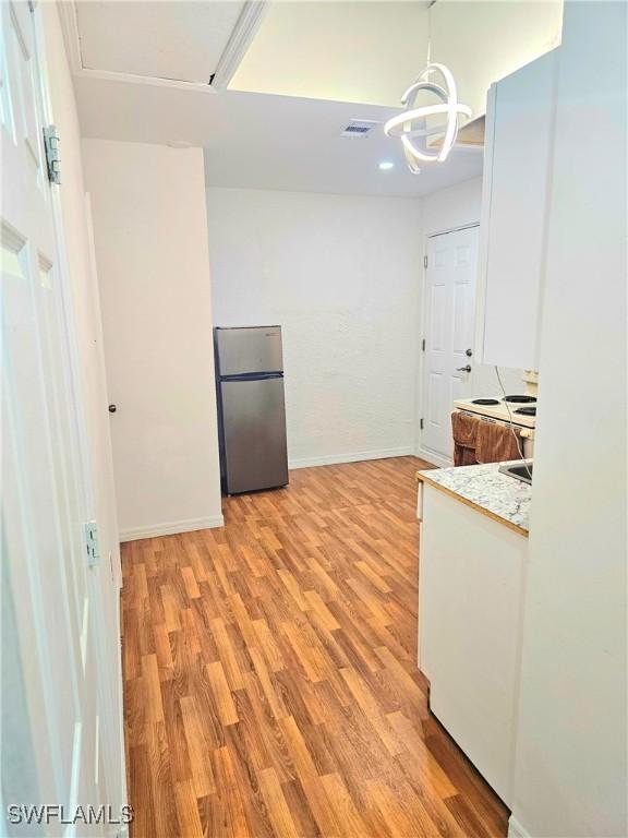 303 E 7th St, Lehigh Acres, FL 33972 - kitchen featuring freestanding refrigerator, light wood-type flooring, baseboards, a chandelier, and hanging light fixtures