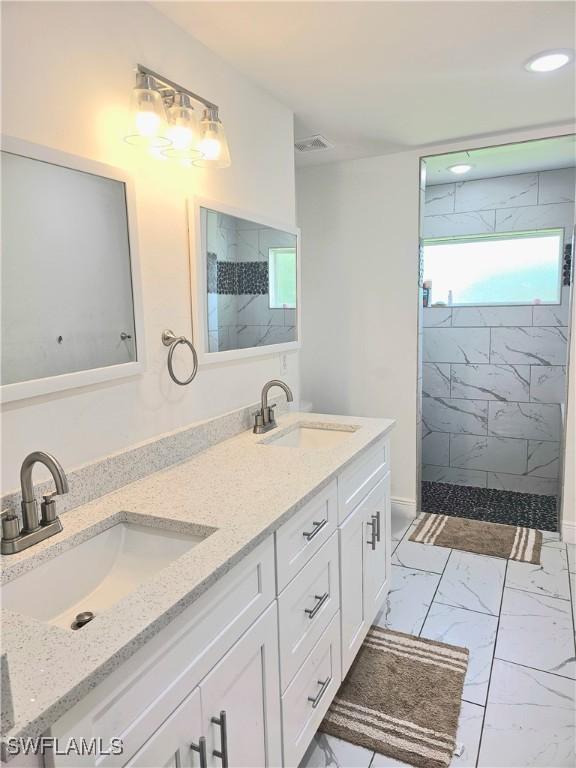303 E 7th St, Lehigh Acres, FL 33972 - full bathroom with a marble finish shower, double vanity, and marble look tiles