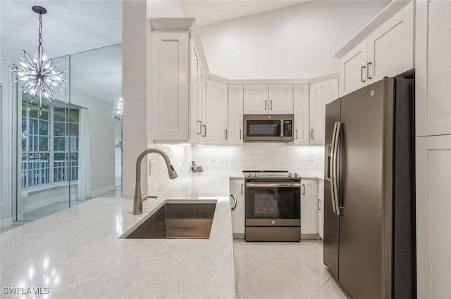 74 Silver Oaks Cir Unit 9-202, Naples, FL 34119 - kitchen with stainless steel appliances, a sink, a chandelier, tasteful backsplash, and white cabinetry