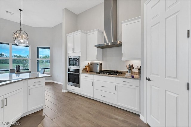 15889 Cranes Marsh Ct, Punta Gorda, FL 33982 - kitchen with appliances with stainless steel finishes, wall chimney exhaust hood, white cabinetry, light stone countertops, and decorative light fixtures