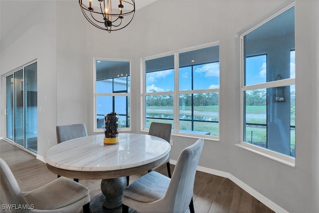 15889 Cranes Marsh Ct, Punta Gorda, FL 33982 - dining room with a chandelier, wood finished floors, baseboards, a water view, and a towering ceiling