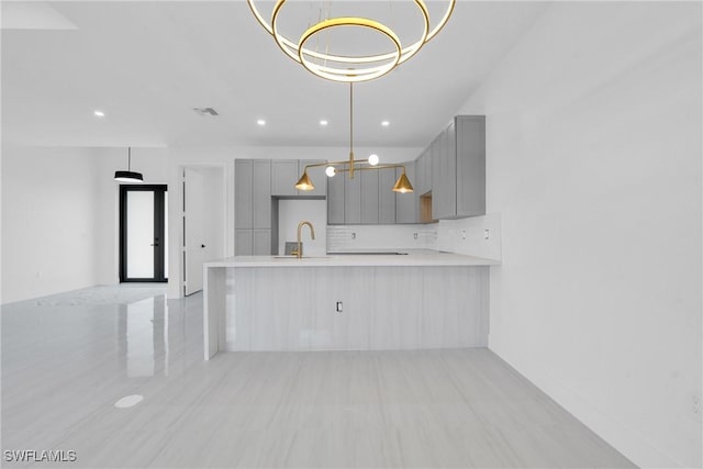 331 Naples Ave S, Lehigh Acres, FL 33974 - kitchen with gray cabinetry, light countertops, a chandelier, a sink, and tasteful backsplash