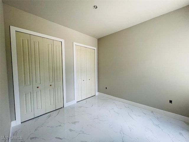 1601 W 9th St, Lehigh Acres, FL 33972 - unfurnished bedroom with light marble finish flooring, two closets, and baseboards