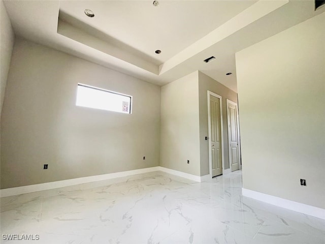 1601 W 9th St, Lehigh Acres, FL 33972 - spare room featuring baseboards, light marble finish flooring, and a tray ceiling