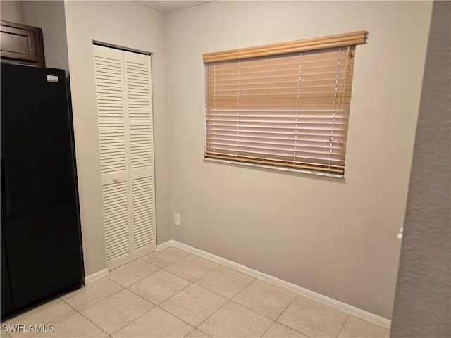 605 Squire Cir Unit 203, Naples, FL 34104 - unfurnished bedroom with freestanding refrigerator, a closet, and light tile patterned floors