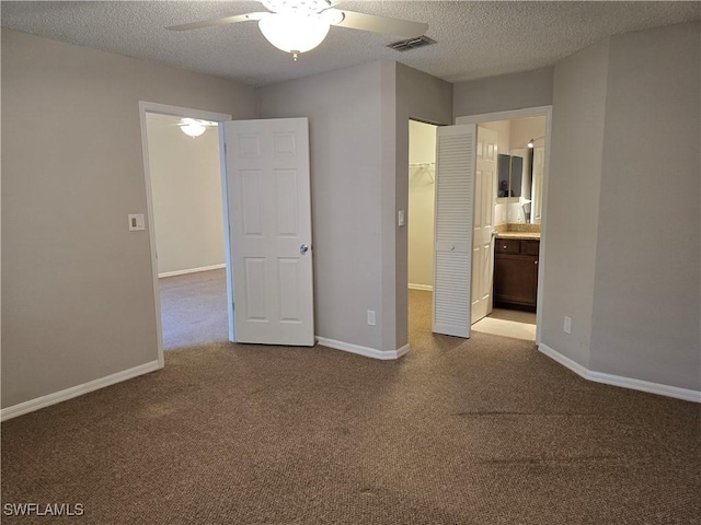 605 Squire Cir Unit 203, Naples, FL 34104 - unfurnished bedroom with carpet floors, a spacious closet, a textured ceiling, connected bathroom, and ceiling fan