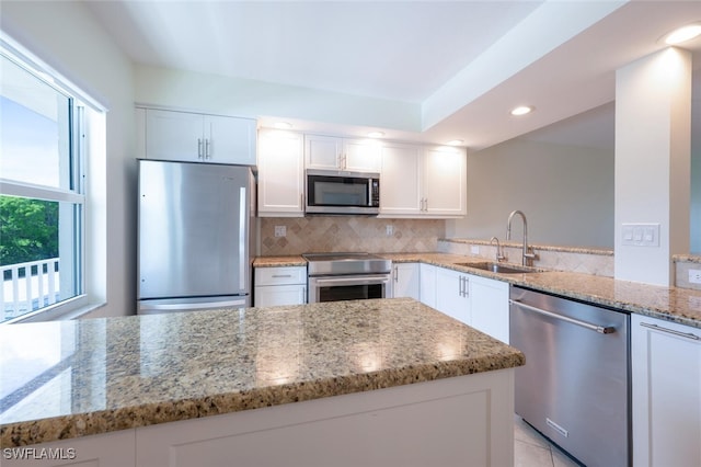 3055 Riviera Dr Unit 306, Naples, FL 34103 - kitchen with appliances with stainless steel finishes, a sink, white cabinets, decorative backsplash, and light stone counters