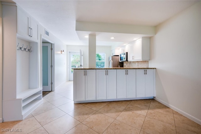3055 Riviera Dr Unit 306, Naples, FL 34103 - kitchen featuring stainless steel appliances, a peninsula, white cabinets, stone countertops, and light tile patterned floors