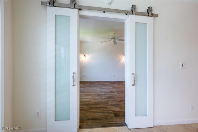 3055 Riviera Dr Unit 306, Naples, FL 34103 - unfurnished room featuring a barn door, wood finished floors, ceiling fan, and baseboards