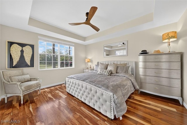 1940 Willow Bend Cir Unit 102, Naples, FL 34109 - bedroom with a tray ceiling, wood finished floors, and a ceiling fan