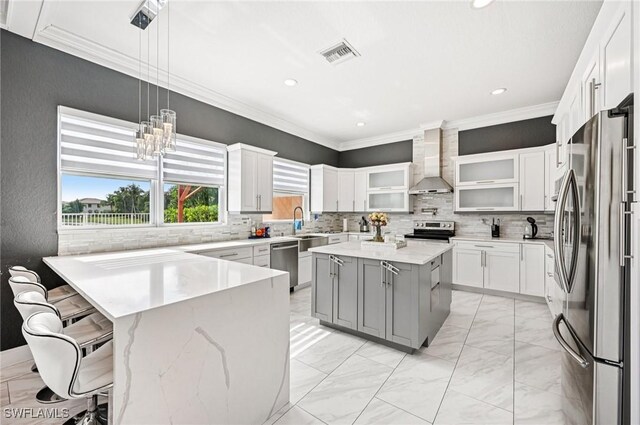 7082 Aliso Ave, West Palm Beach, FL 33413 - kitchen with stainless steel appliances, wall chimney exhaust hood, ornamental molding, light marble finish flooring, and glass insert cabinets