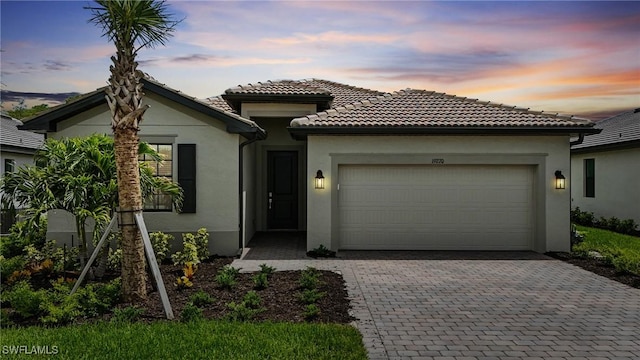 19270 Hinkley Dr, Estero, FL 33928 - mediterranean / spanish home featuring a garage, stucco siding, and decorative driveway