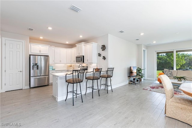 1050 Enbrook Loop, Naples, FL 34114 - kitchen featuring appliances with stainless steel finishes, open floor plan, a peninsula, a kitchen breakfast bar, and light countertops
