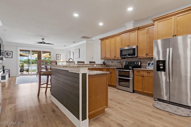 12455 Muddy Creek Ln, Fort Myers, FL 33913 - kitchen featuring appliances with stainless steel finishes, ornamental molding, light wood finished floors, a ceiling fan, and a breakfast bar