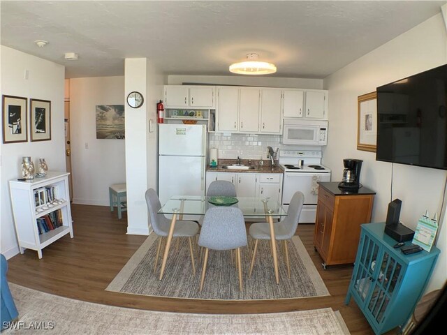 7360 Estero Blvd Unit 1102, Fort Myers Beach, FL 33931 - kitchen with white appliances, a sink, dark wood-style floors, white cabinets, and tasteful backsplash