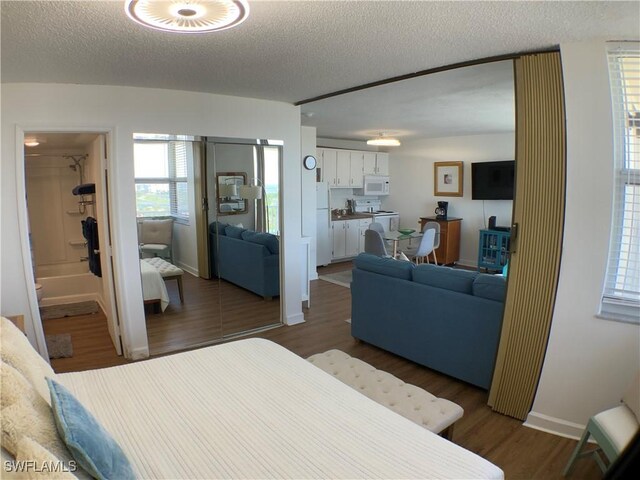 7360 Estero Blvd Unit 1102, Fort Myers Beach, FL 33931 - bedroom with freestanding refrigerator, a textured ceiling, multiple windows, and dark wood-style flooring