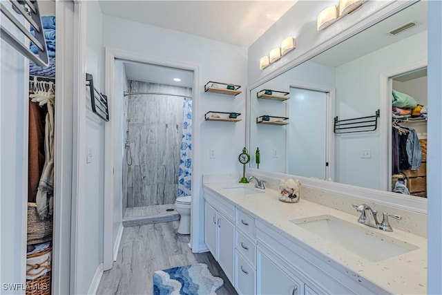 164 Belina Dr E Unit 4, Naples, FL 34104 - bathroom featuring a walk in closet, double vanity, a stall shower, and wood finished floors