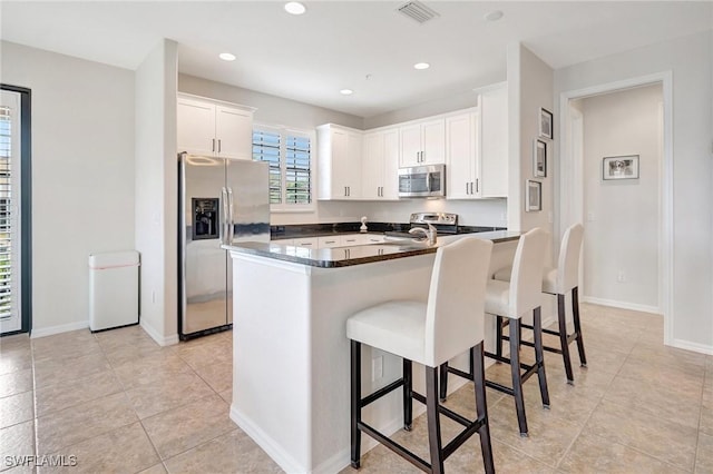 11830 Paseo Grande Blvd Unit 4608, Fort Myers, FL 33912 - kitchen with appliances with stainless steel finishes, a kitchen breakfast bar, white cabinets, dark countertops, and light tile patterned floors