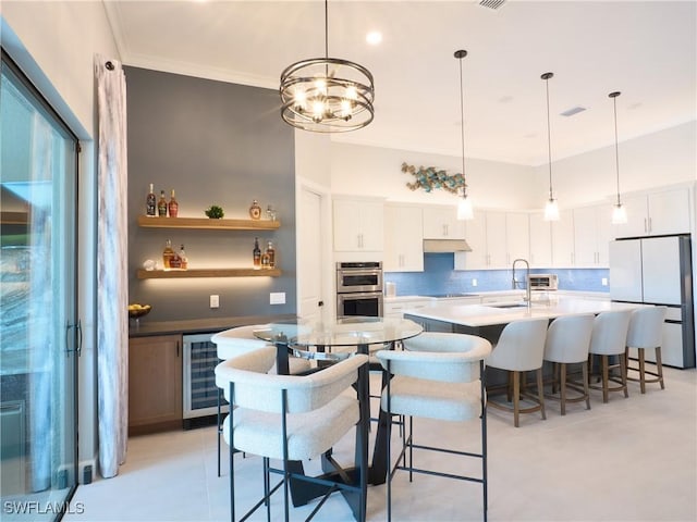 19449 The Place Blvd, Estero, FL 33928 - kitchen with freestanding refrigerator, beverage cooler, a kitchen island with sink, a sink, and stainless steel double oven