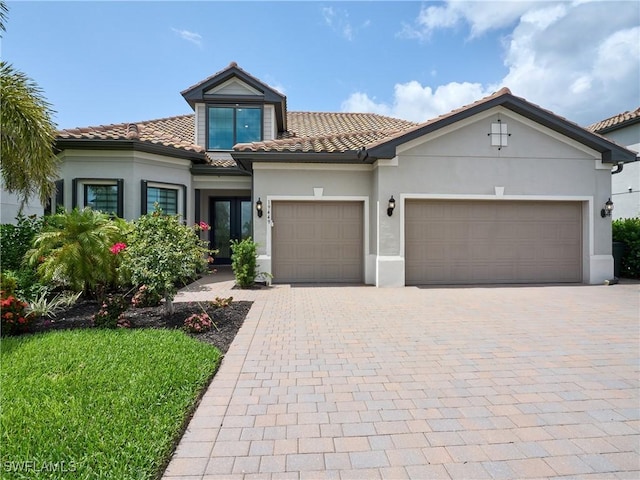 19449 The Place Blvd, Estero, FL 33928 - mediterranean / spanish home with a garage, decorative driveway, stucco siding, and a tiled roof