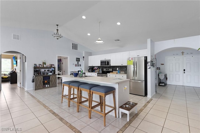 866 Carbon St E, Lehigh Acres, FL 33974 - kitchen with appliances with stainless steel finishes, arched walkways, light tile patterned floors, light countertops, and white cabinetry