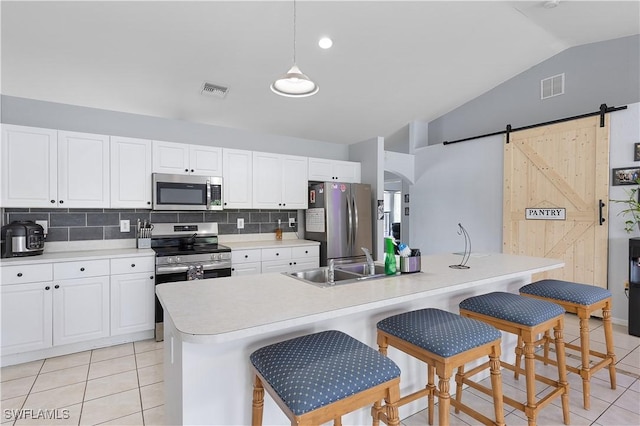 866 Carbon St E, Lehigh Acres, FL 33974 - kitchen featuring appliances with stainless steel finishes, a sink, vaulted ceiling, light tile patterned flooring, and a barn door