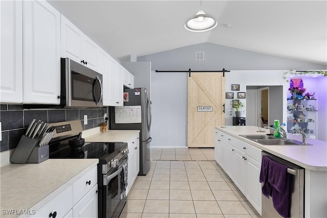 866 Carbon St E, Lehigh Acres, FL 33974 - kitchen featuring appliances with stainless steel finishes, lofted ceiling, a barn door, tasteful backsplash, and light countertops