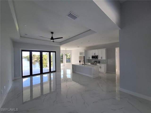 4956 30th Pl SW, Naples, FL 34116 - living area with a tray ceiling, baseboards, ceiling fan, and light marble finish floors