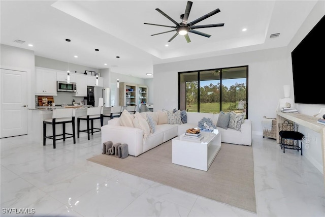 4119 43rd Ave NE, Naples, FL 34120 - living room featuring a raised ceiling, recessed lighting, a ceiling fan, and light marble finish floors