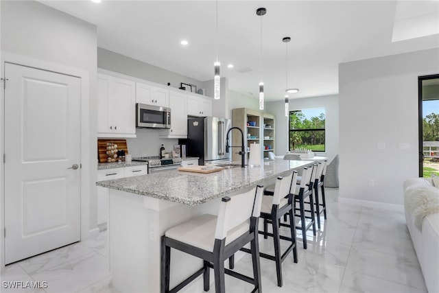 4119 43rd Ave NE, Naples, FL 34120 - kitchen featuring stainless steel appliances, light marble finish floors, a large island, white cabinets, and a breakfast bar area