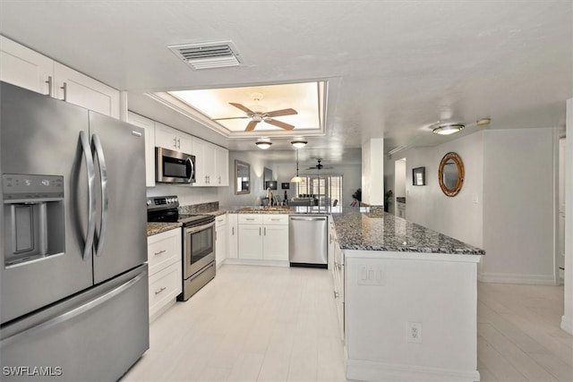 12541 Kelly Sands Way Unit 19, Fort Myers, FL 33908 - kitchen featuring stainless steel appliances, a peninsula, white cabinets, dark stone counters, and a tray ceiling