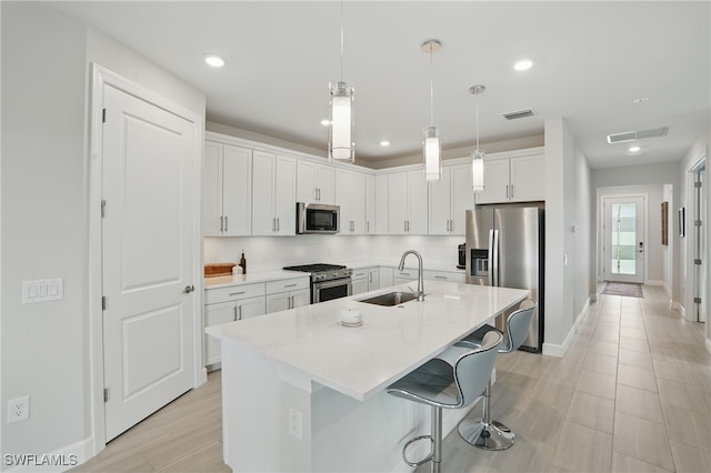 1870 Amador Ct, Naples, FL 34120 - kitchen with appliances with stainless steel finishes, white cabinetry, light countertops, an island with sink, and a breakfast bar area