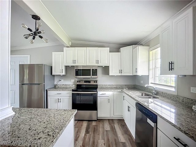 93 E Mariana Ave, North Fort Myers, FL 33917 - kitchen featuring appliances with stainless steel finishes, ornamental molding, wood finished floors, white cabinetry, and light stone counters