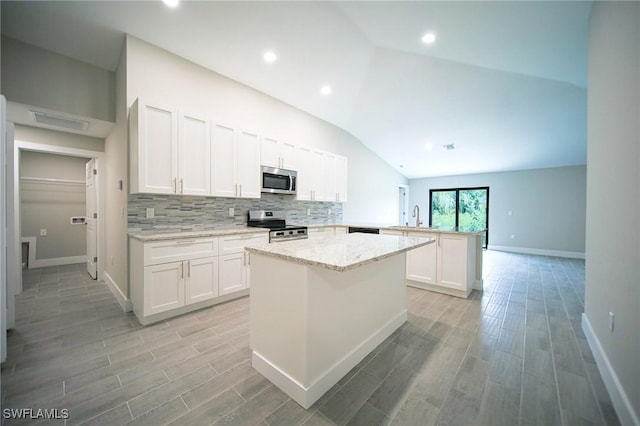 374 Pennfield St, Lehigh Acres, FL 33974 - kitchen featuring stainless steel appliances, a peninsula, a sink, vaulted ceiling, and tasteful backsplash