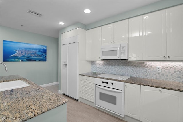 740 N Collier Blvd Unit 206, Marco Island, FL 34145 - kitchen with white appliances, a sink, white cabinetry, stone countertops, and decorative backsplash