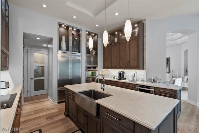 12147 Colliers Reserve Dr, Naples, FL 34110 - kitchen featuring arched walkways, stainless steel appliances, a sink, light wood-style flooring, and recessed lighting