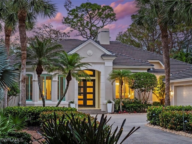 12147 Colliers Reserve Dr, Naples, FL 34110 - view of front of home with a chimney, a tile roof, stucco siding, a garage, and driveway