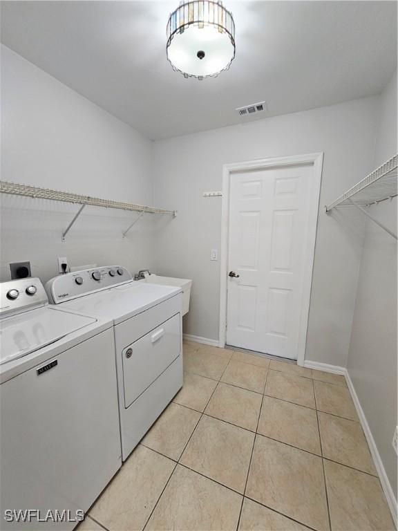 1221 SW 10th Ter, Cape Coral, FL 33991 - laundry room featuring washer and dryer, light tile patterned floors, and baseboards