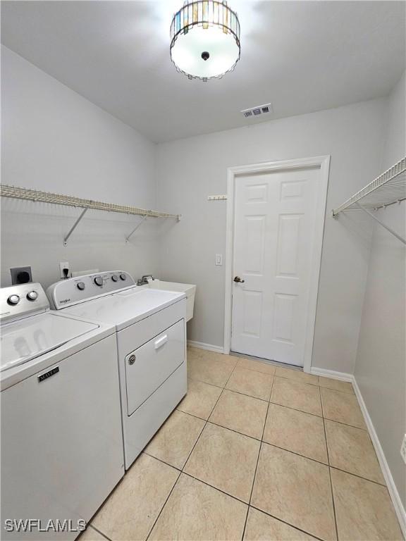 1221 SW 10th Ter, Cape Coral, FL 33991 - laundry area featuring washer and dryer, light tile patterned floors, and baseboards