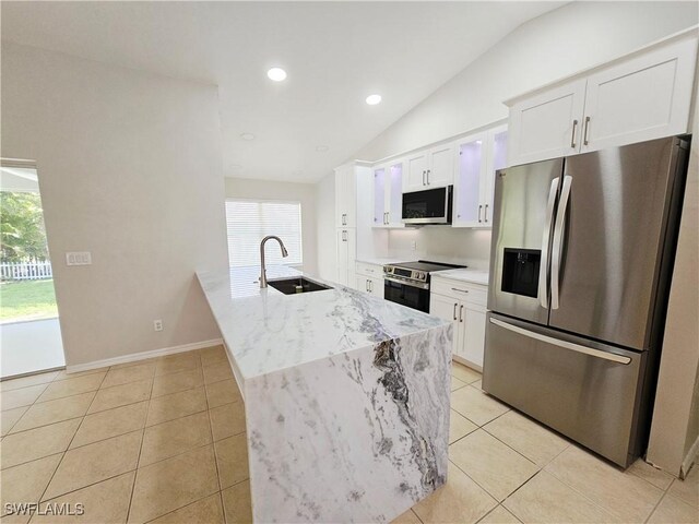 1221 SW 10th Ter, Cape Coral, FL 33991 - kitchen featuring appliances with stainless steel finishes, a sink, vaulted ceiling, white cabinetry, and light tile patterned floors