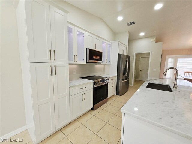 1221 SW 10th Ter, Cape Coral, FL 33991 - kitchen with appliances with stainless steel finishes, a sink, white cabinetry, light tile patterned flooring, and glass insert cabinets