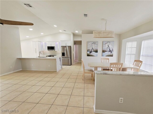 1221 SW 10th Ter, Cape Coral, FL 33991 - kitchen featuring appliances with stainless steel finishes, a peninsula, white cabinets, light tile patterned floors, and lofted ceiling